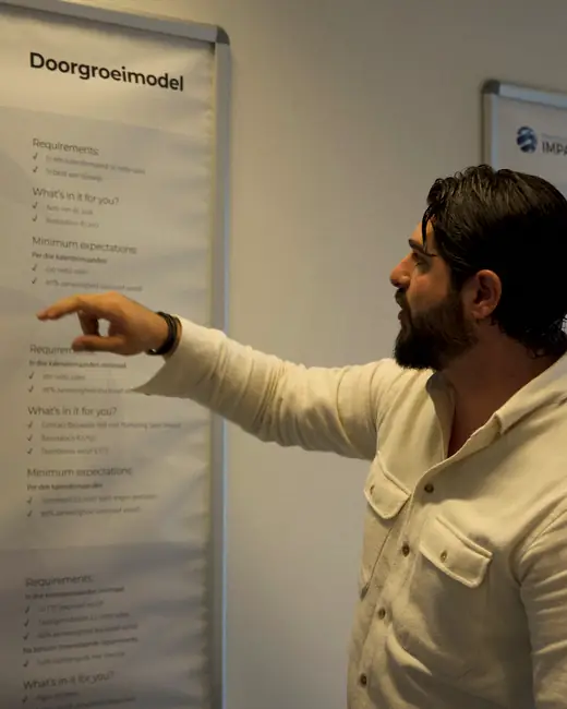Trainer van MSI wijst op het doorgroeimodel aan de muur