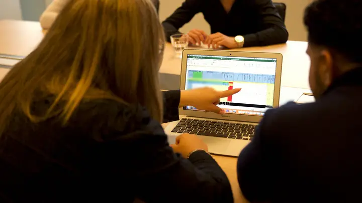 Collega's van MSI kijken samen naar uren en sales op een laptop